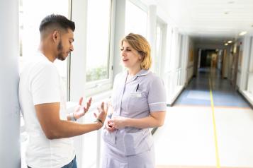 Two people speaking in a corridor